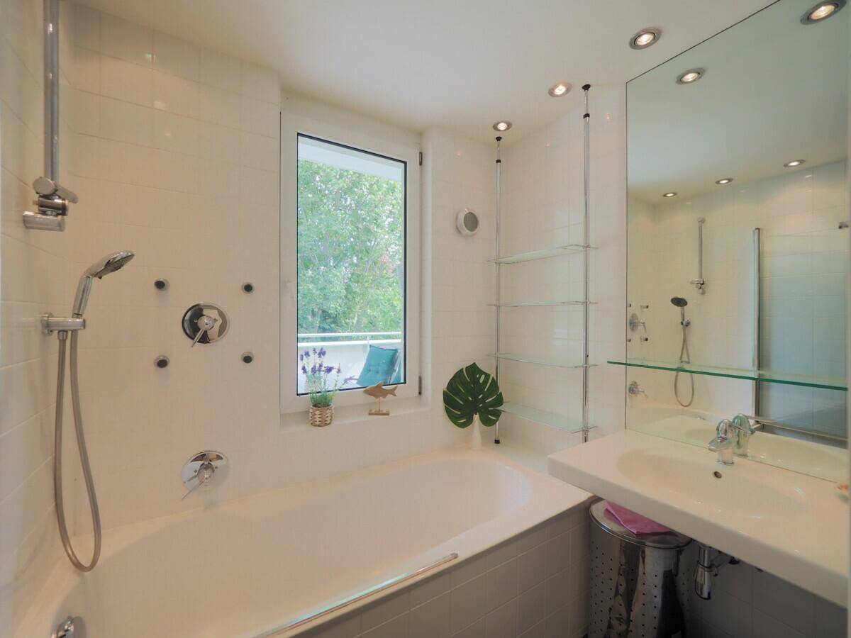 Modernes Badezimmer mit Badewanne, Dusche und Fenster für natürliche Belüftung und Licht.