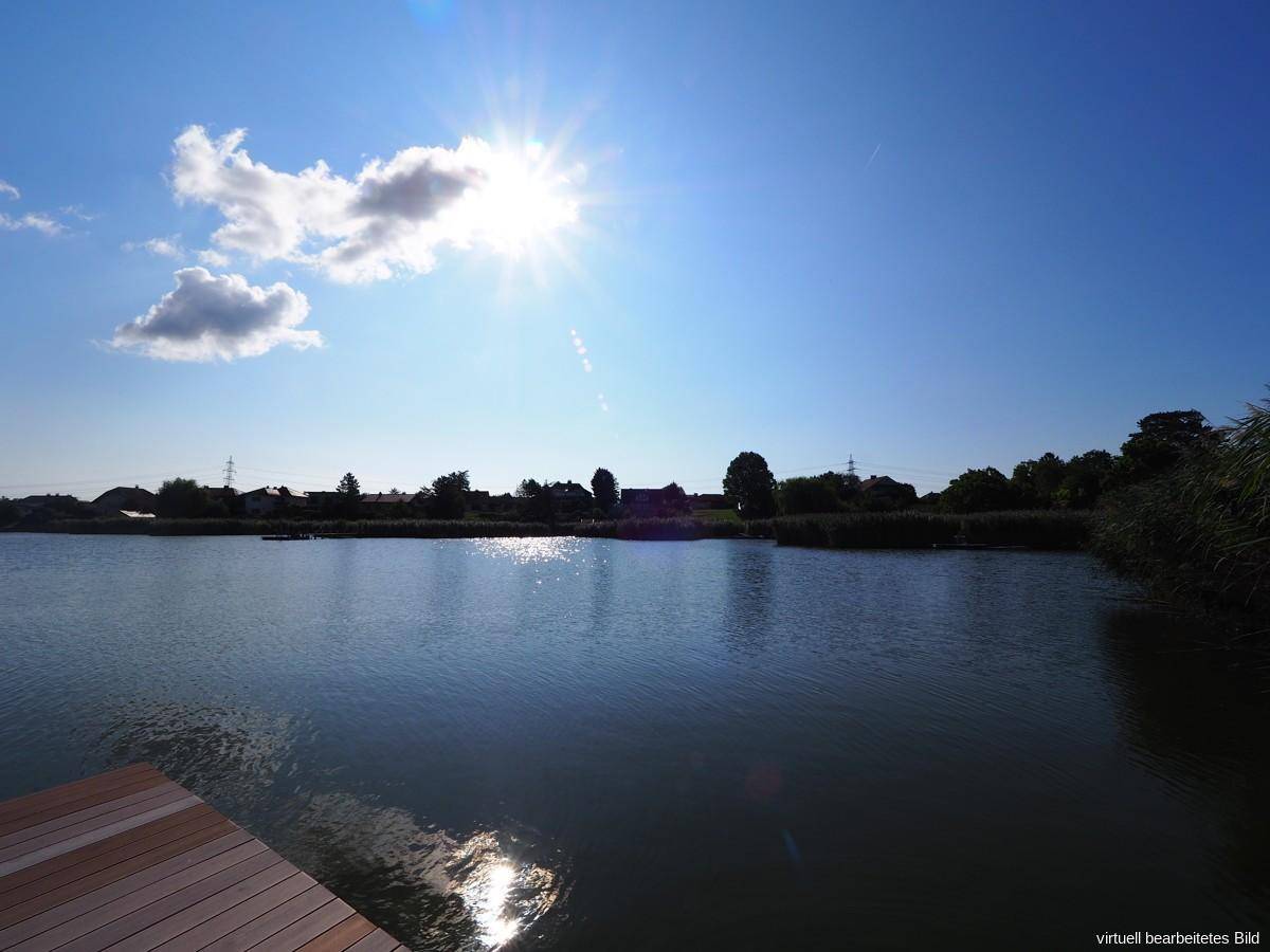 Weitläufiger Blick über den See an einem sonnigen Tag mit blauem Himmel.