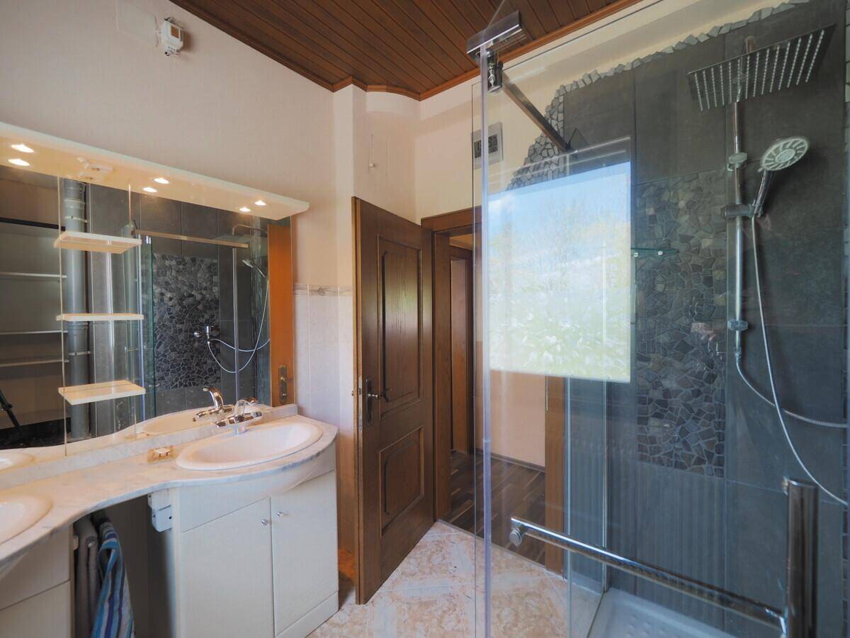 Badezimmer mit Doppelwaschbecken, großem Spiegel und begehbarer Dusche, hell und funktional.