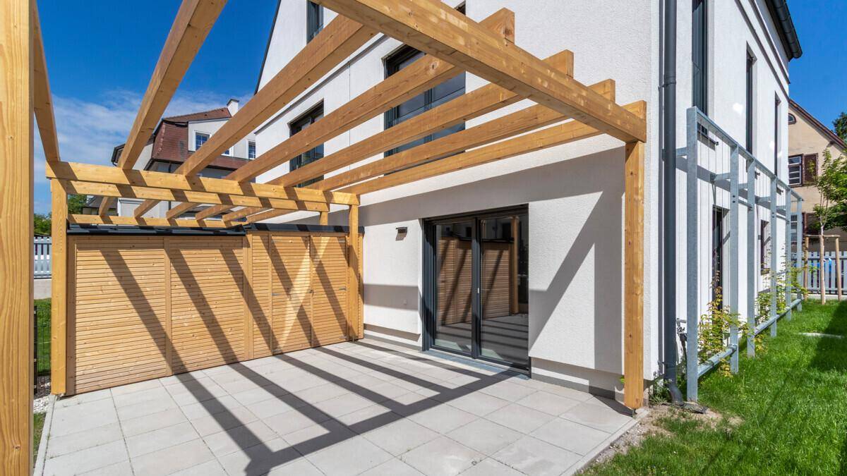 Sonniger Terrassenbereich mit Holzpergola und direktem Zugang zum Haus.