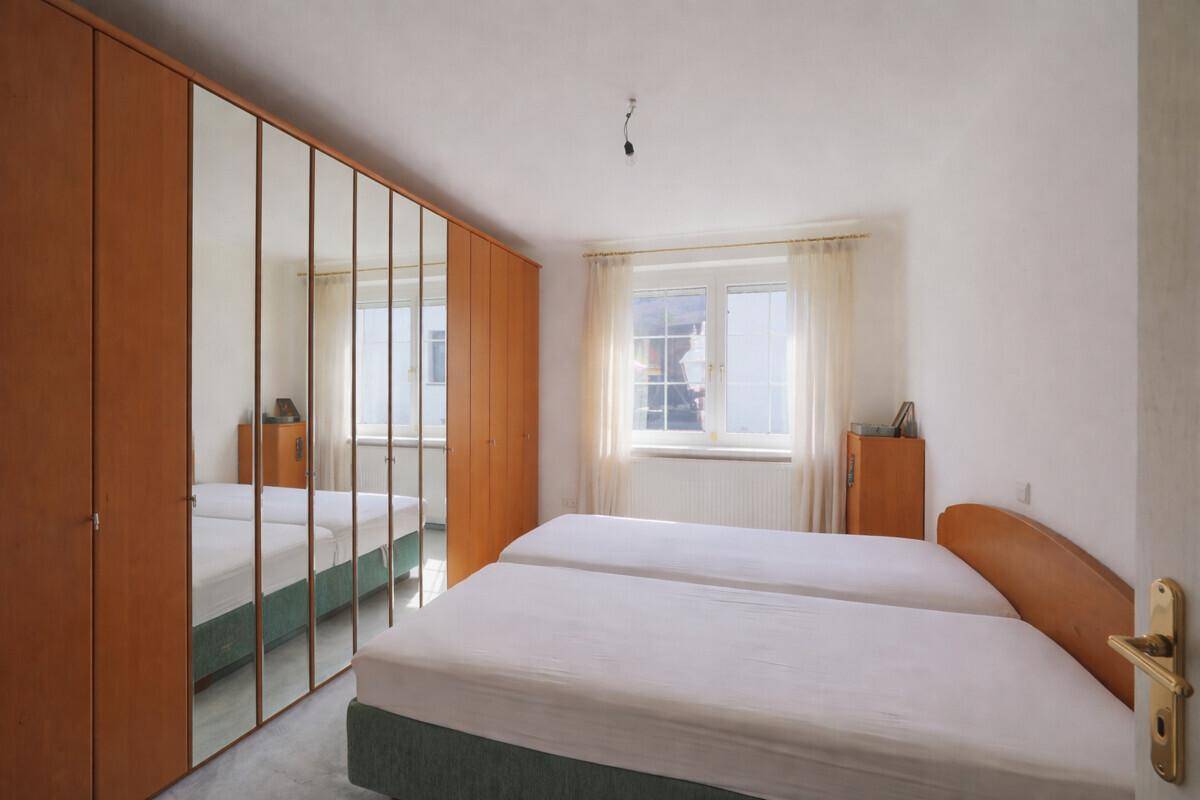 Schlafzimmer mit Doppelbett, Spiegelschränken und Fenster mit Blick ins Grüne.