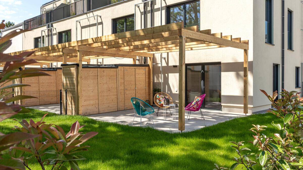 Gemütliche Terrasse mit Holzpergola, bunten Sitzgelegenheiten und Blick ins Grüne.