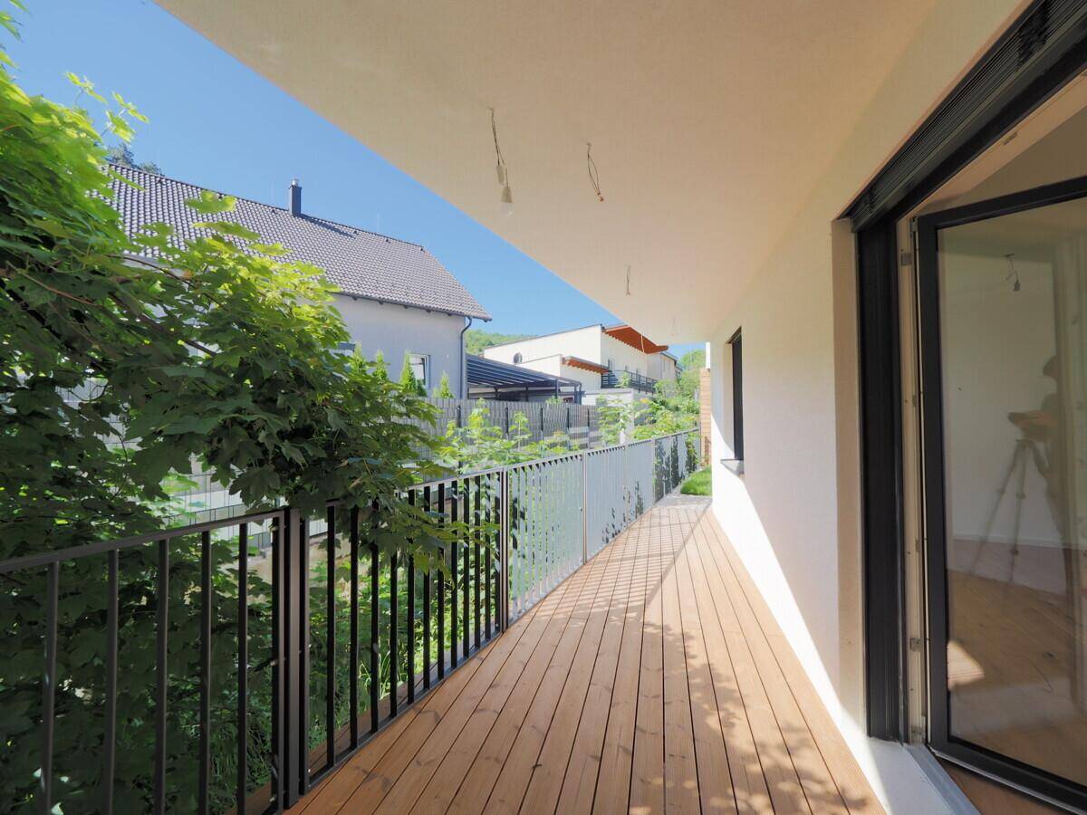 Langer Balkon mit Holzboden und Blick ins Grüne.