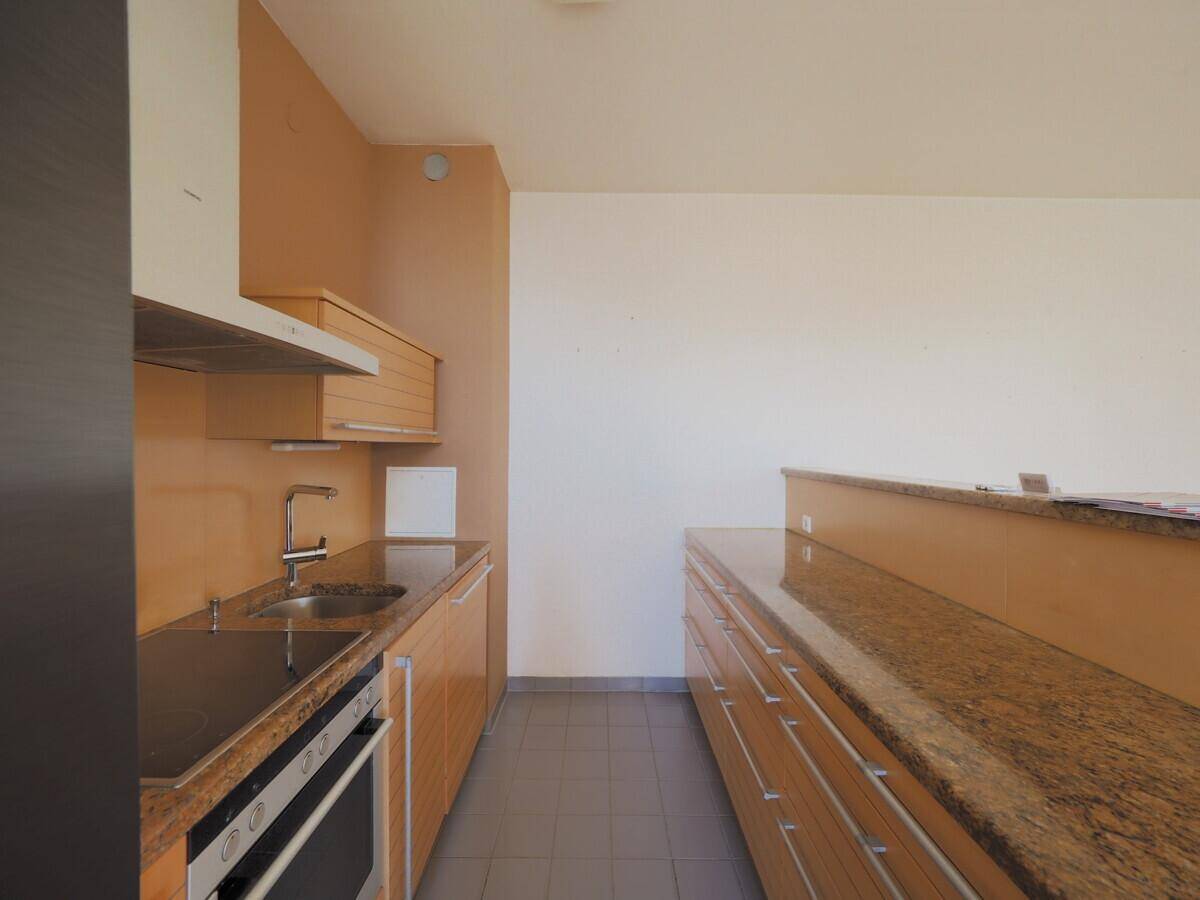 Funktionale Küche mit Granitarbeitsplatten, Holzschränken und integrierten Geräten.