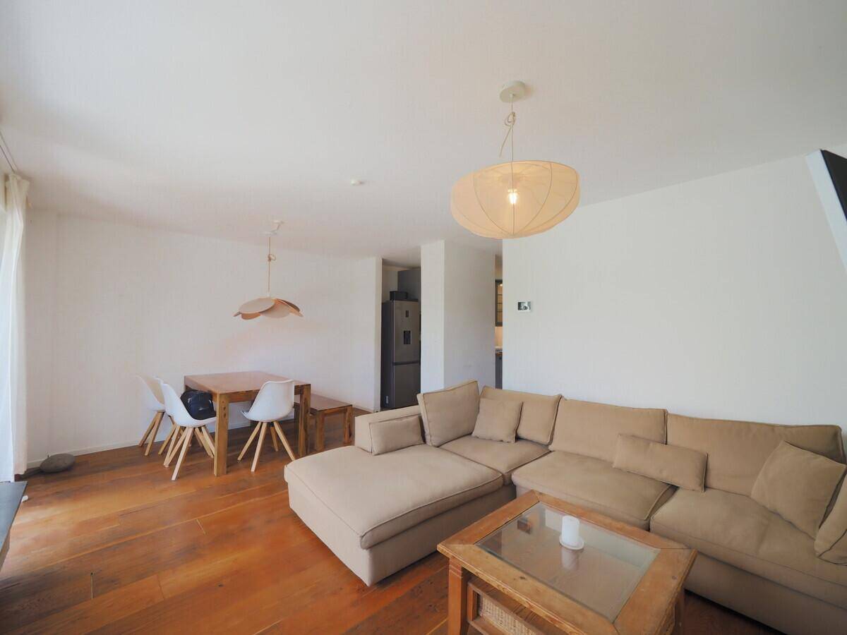 Geräumiger Wohnbereich mit bequemer Couch, Esstisch und Zugang zur Küche.