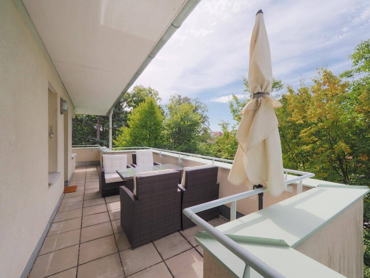 Großer Balkon mit Sonnenschirm und Sitzbereich, ideal zum Entspannen im Freien.