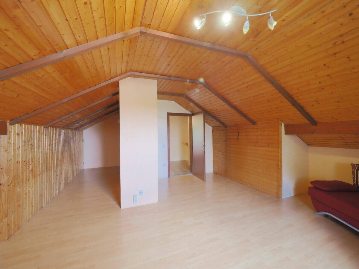 Helles Dachzimmer mit Holzbalken und Laminatboden, bietet vielseitige Nutzungsmöglichkeiten.