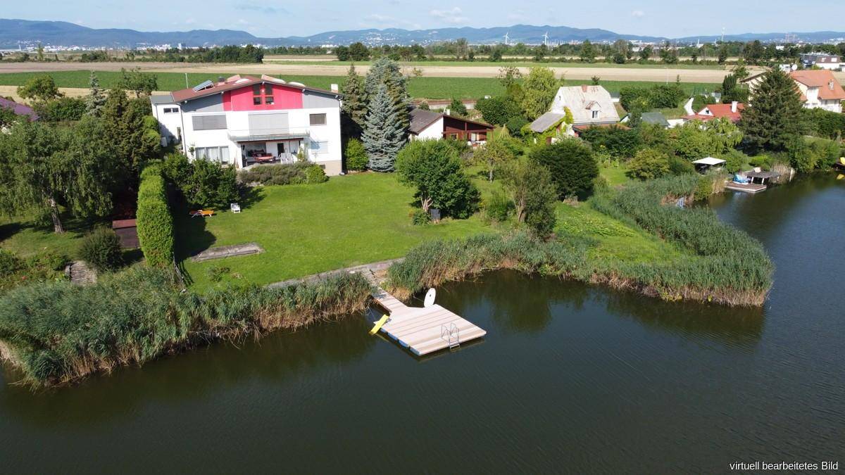 Großzügiges Anwesen am See mit weitläufigem Garten, eigenem Steg und Bergblick im Hintergrund.
