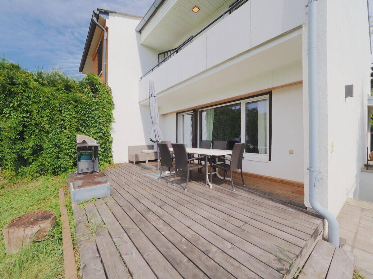 Große Holzterrasse mit Esstisch, Stühlen und Grill für gemütliche Stunden im Freien.