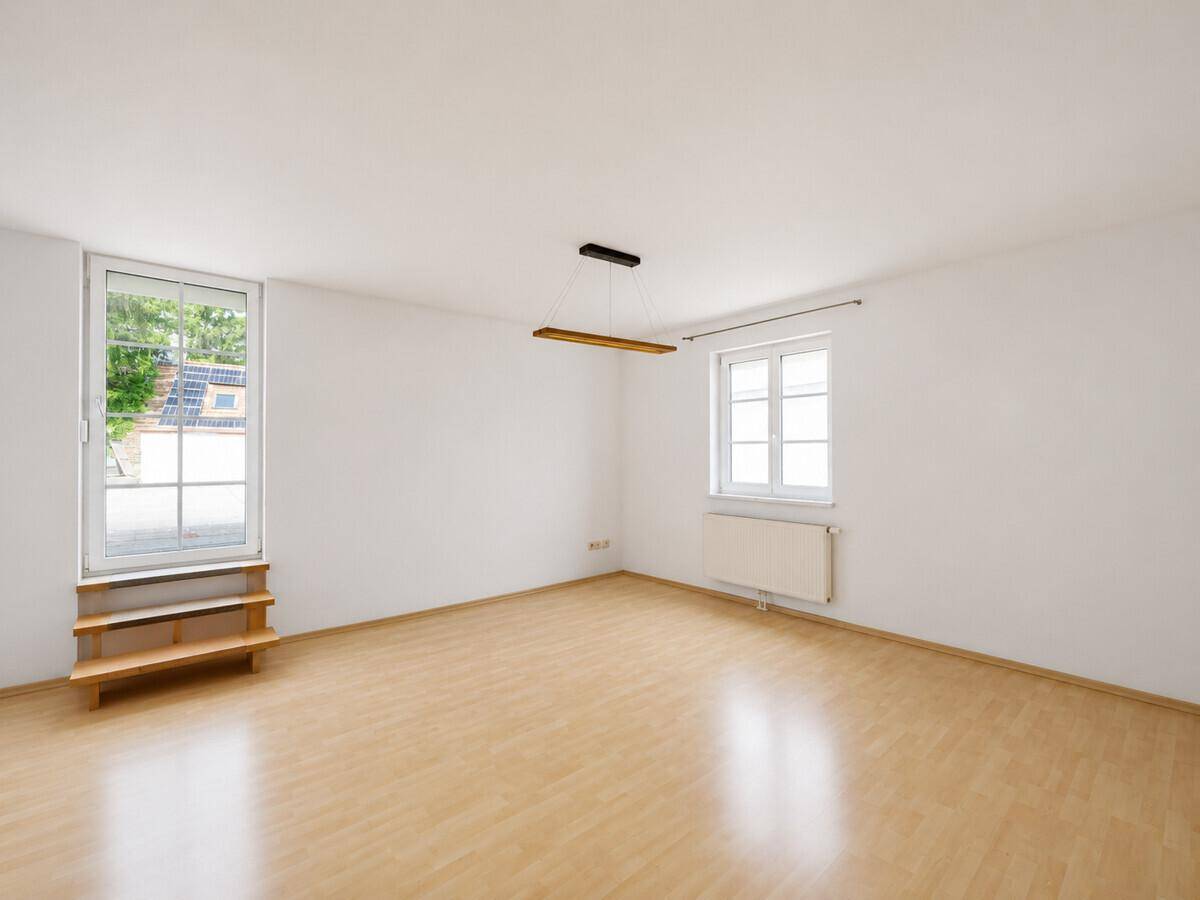 Heller, leerer Raum mit Holzboden und Zugang zu einem Außenbereich.