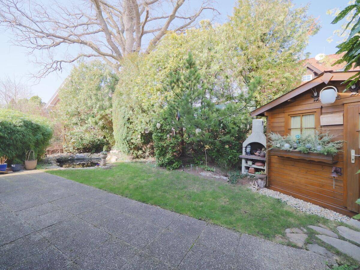 Gepflegter Garten mit Rasenfläche, Gartenhaus und integriertem Grill für gemütliche Abende.