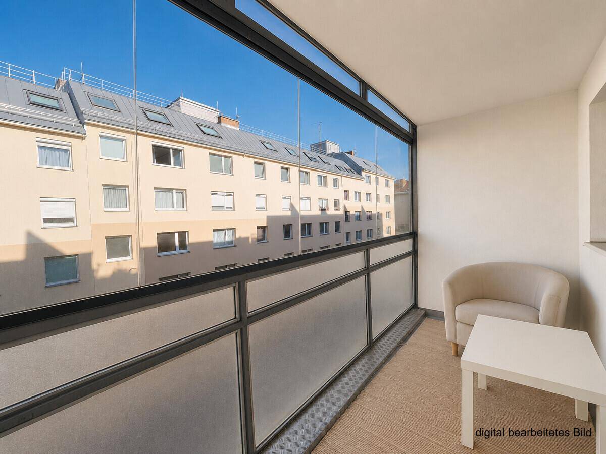 Verglaster Balkon mit Sitzgelegenheiten und Blick auf die umliegenden Gebäude.