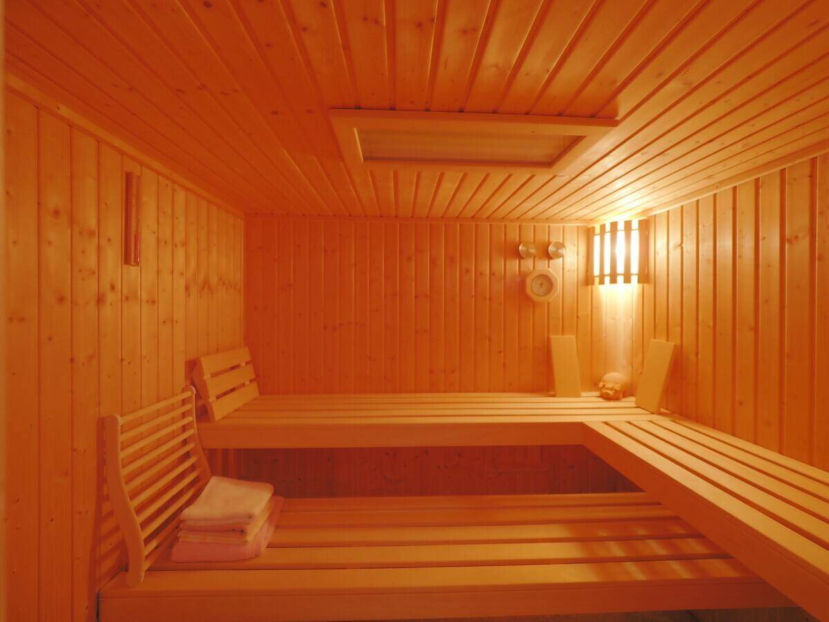 Traditionelle Holzsauna mit mehrstufigen Bänken und stimmungsvoller Beleuchtung für Entspannung.