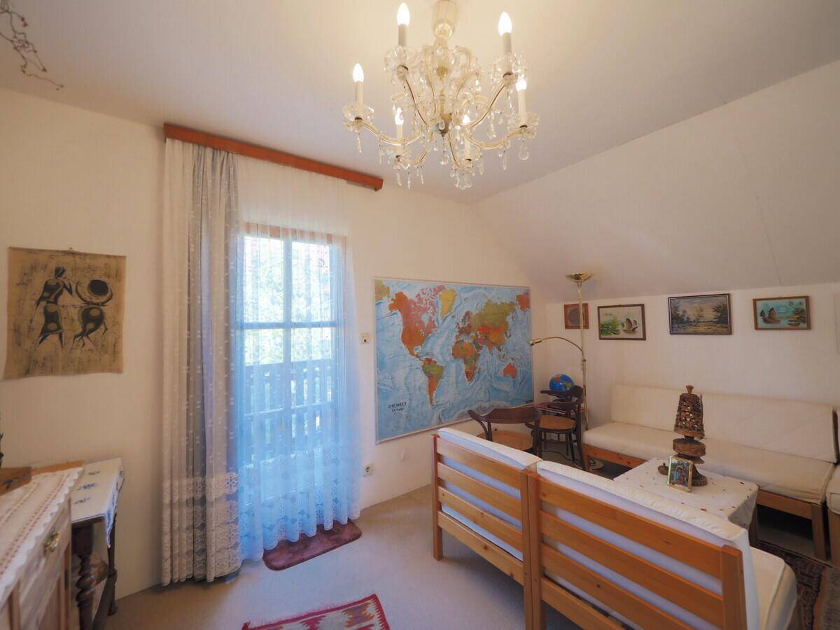 Gemütliches Zimmer mit Dachschräge, Holzbett und Zugang zu einem französischen Balkon.