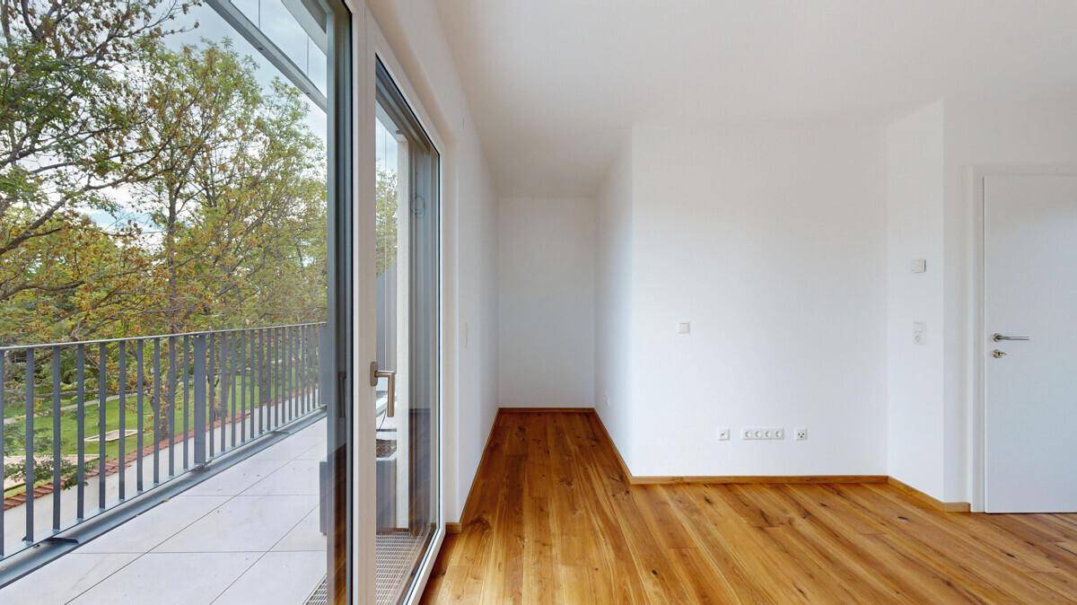 Heller Flur mit Holzboden und direktem Zugang zu einem Balkon mit Metallgeländer.