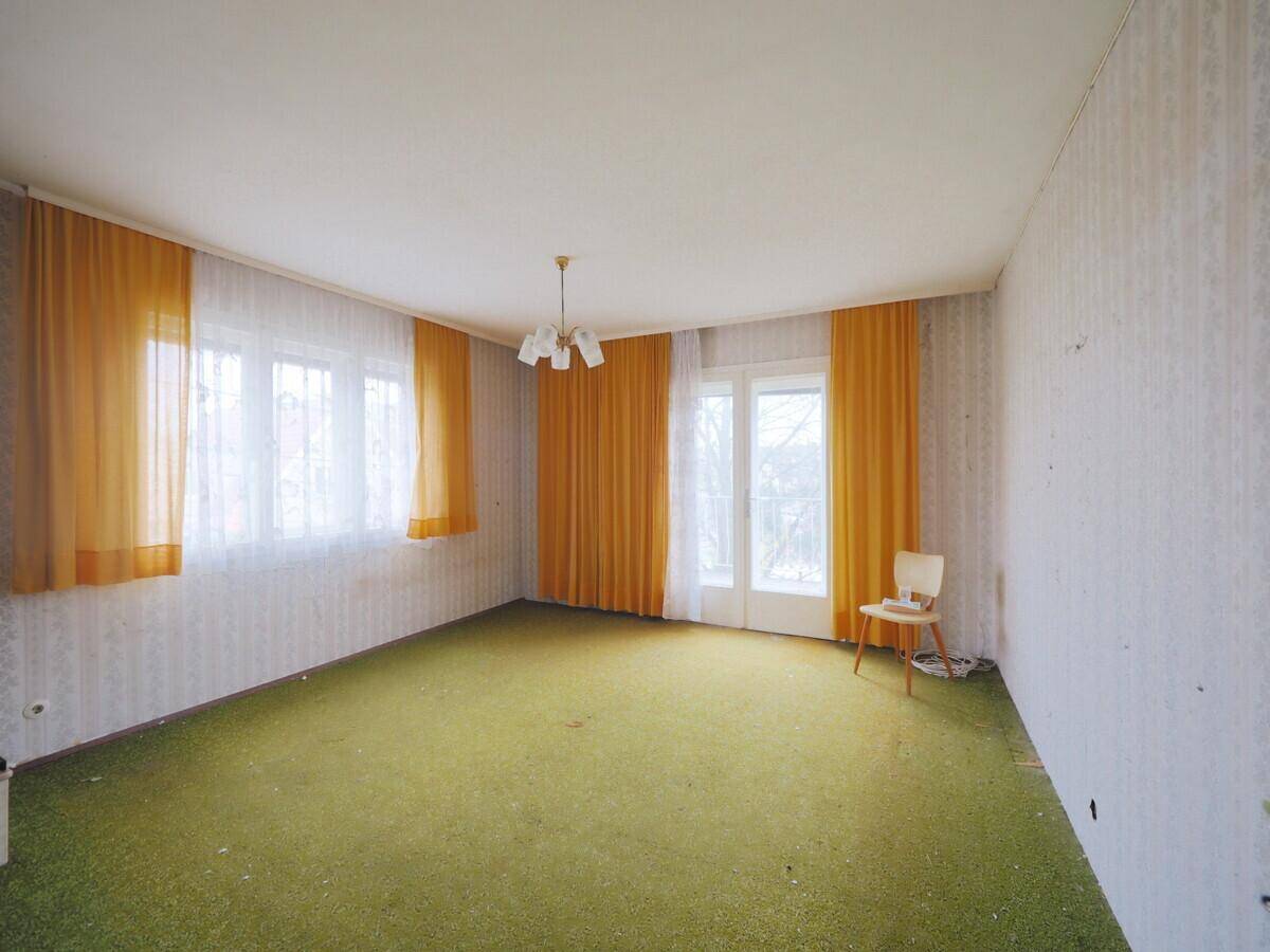 Zimmer mit grünem Teppichboden und gelben Vorhängen, das einen 80er-Jahre-Stil aufweist.