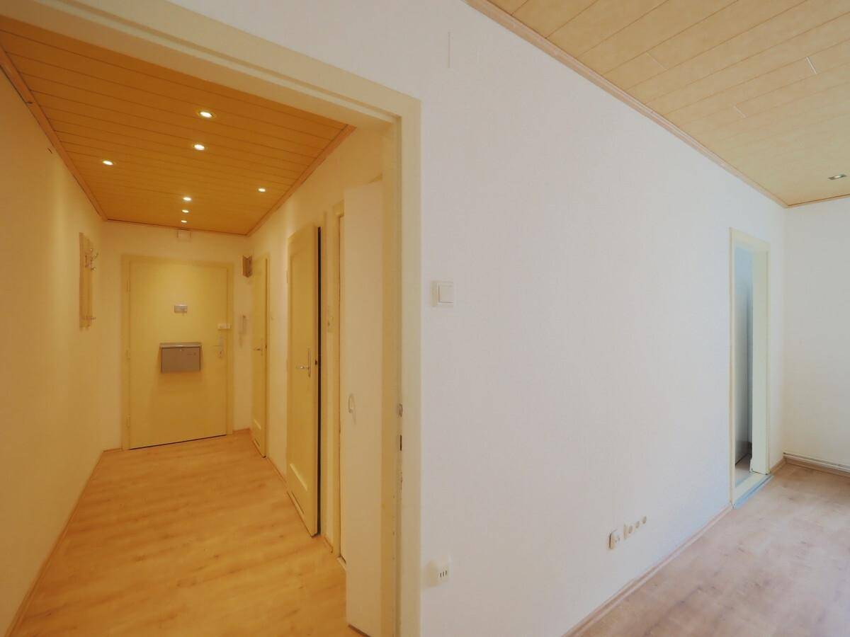 Heller Flur mit Laminatboden, Holzdeckenpaneelen und integrierten Einbaustrahlern.