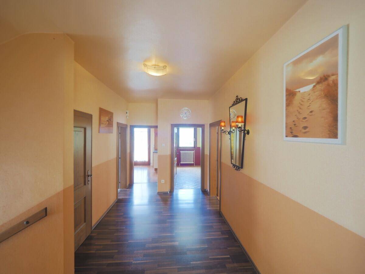 Heller Flur mit dunklem Laminatboden und mehreren Holztüren, die zu anderen Räumen führen.