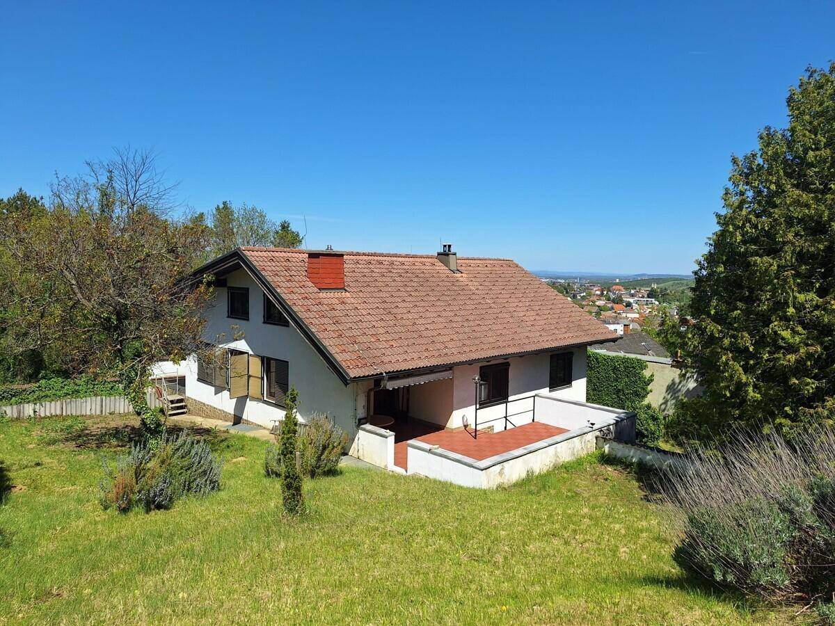 Freistehendes Haus mit Satteldach, großer Terrasse und weitem Blick über die Landschaft.