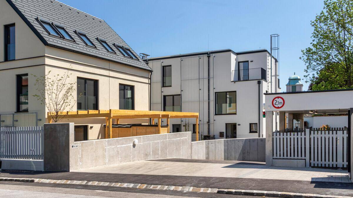 Zufahrt zur Tiefgarage neben modernen Wohngebäuden unter blauem Himmel.