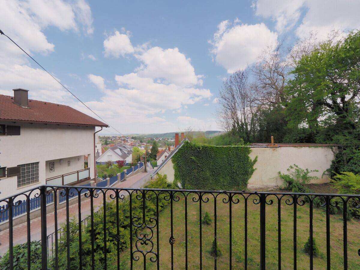 Blick vom Balkon über die Nachbarschaft mit Häusern und viel Grün in der Ferne.
