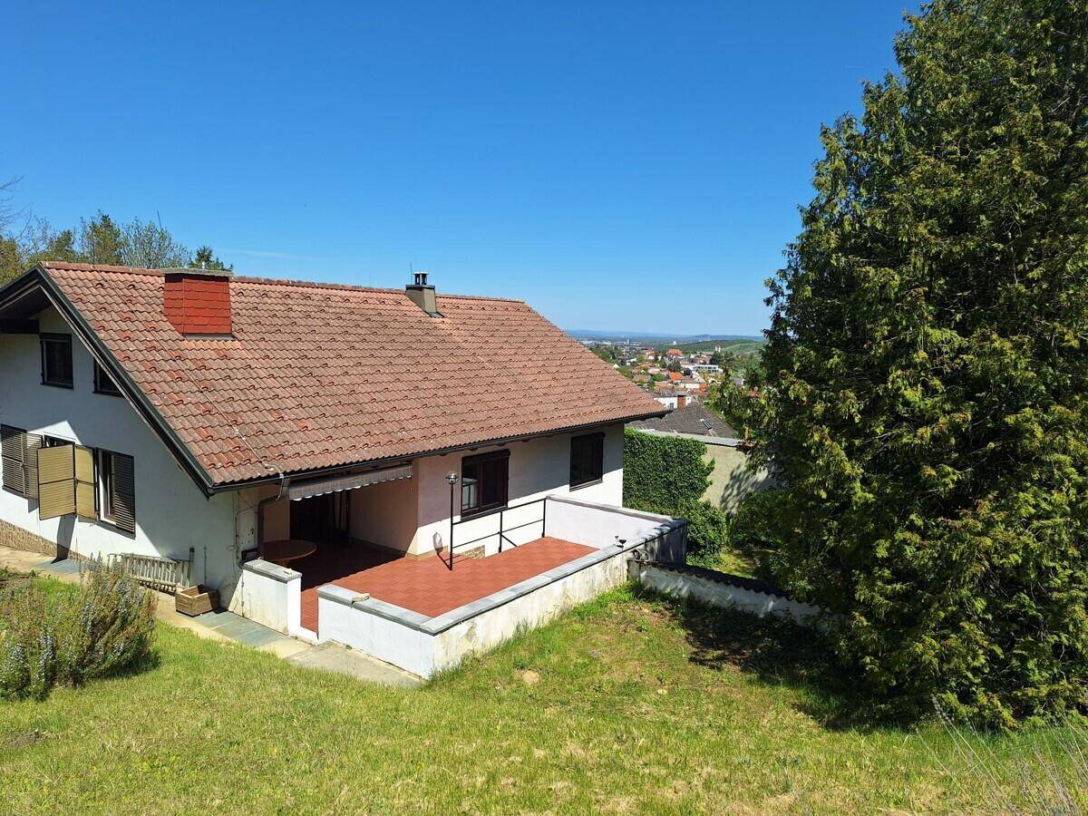 Haus mit Terrasse und Garten, umgeben von viel Grün und mit Fernblick.