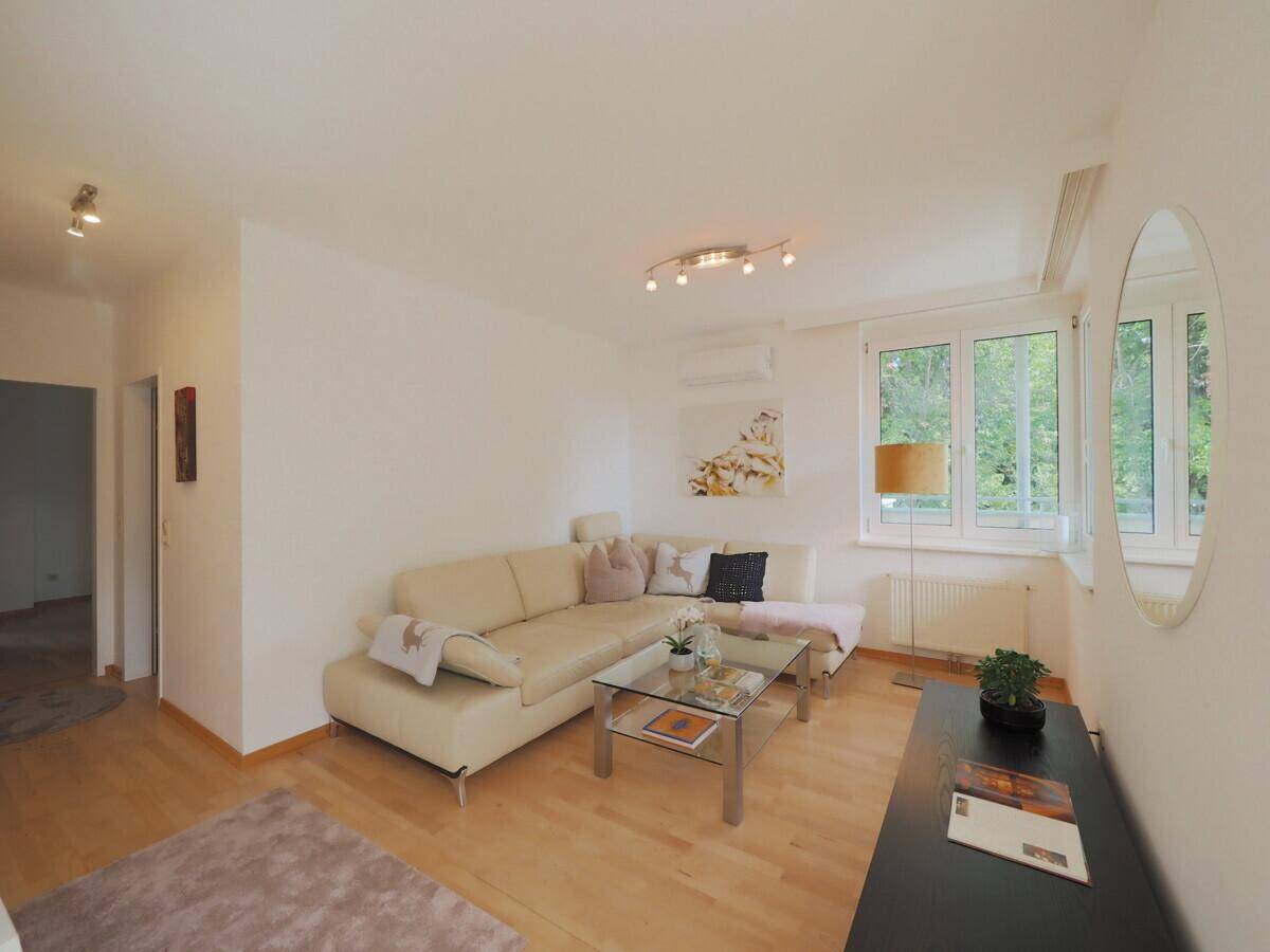 Gemütlicher Wohnbereich mit Ecksofa, Holzboden und großen Fenstern für viel Tageslicht.