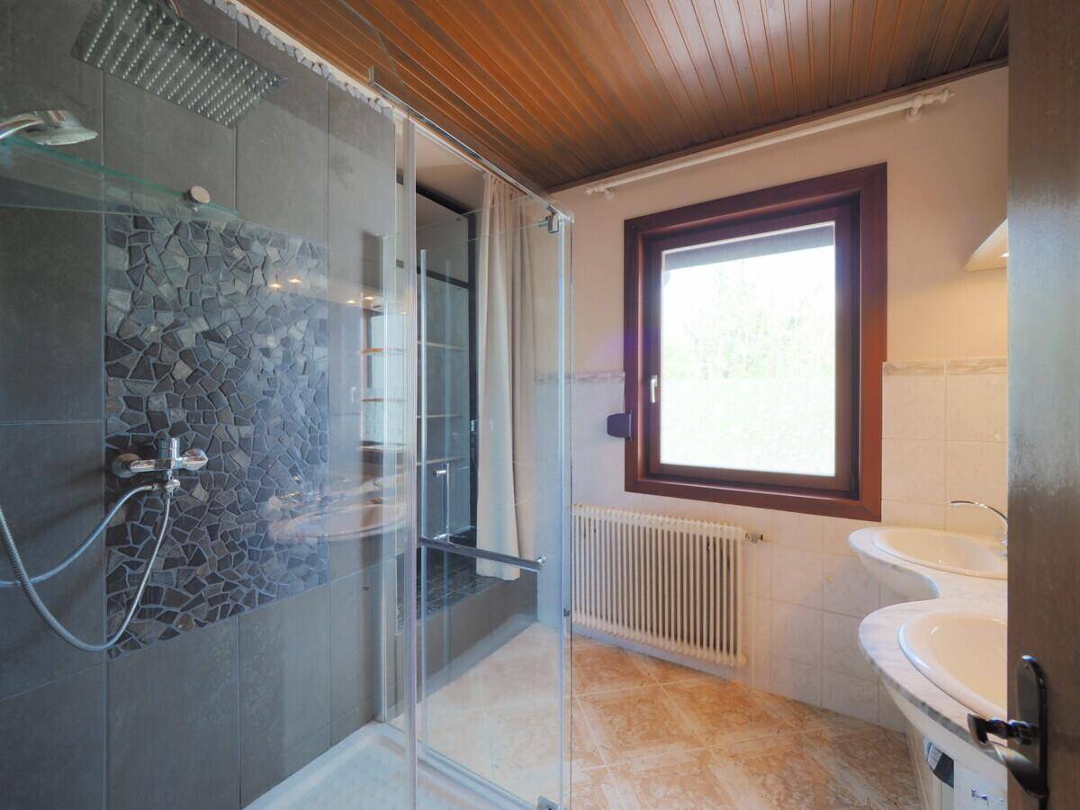 Modernes Badezimmer mit begehbarer Dusche, Doppelwaschbecken und Holzdecke.
