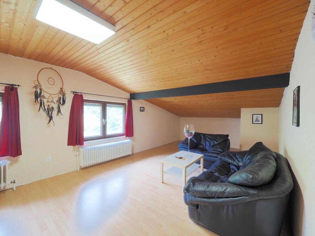 Geräumiges Dachzimmer mit Holzdecke, Laminatboden und zwei Fenstern für viel Tageslicht.