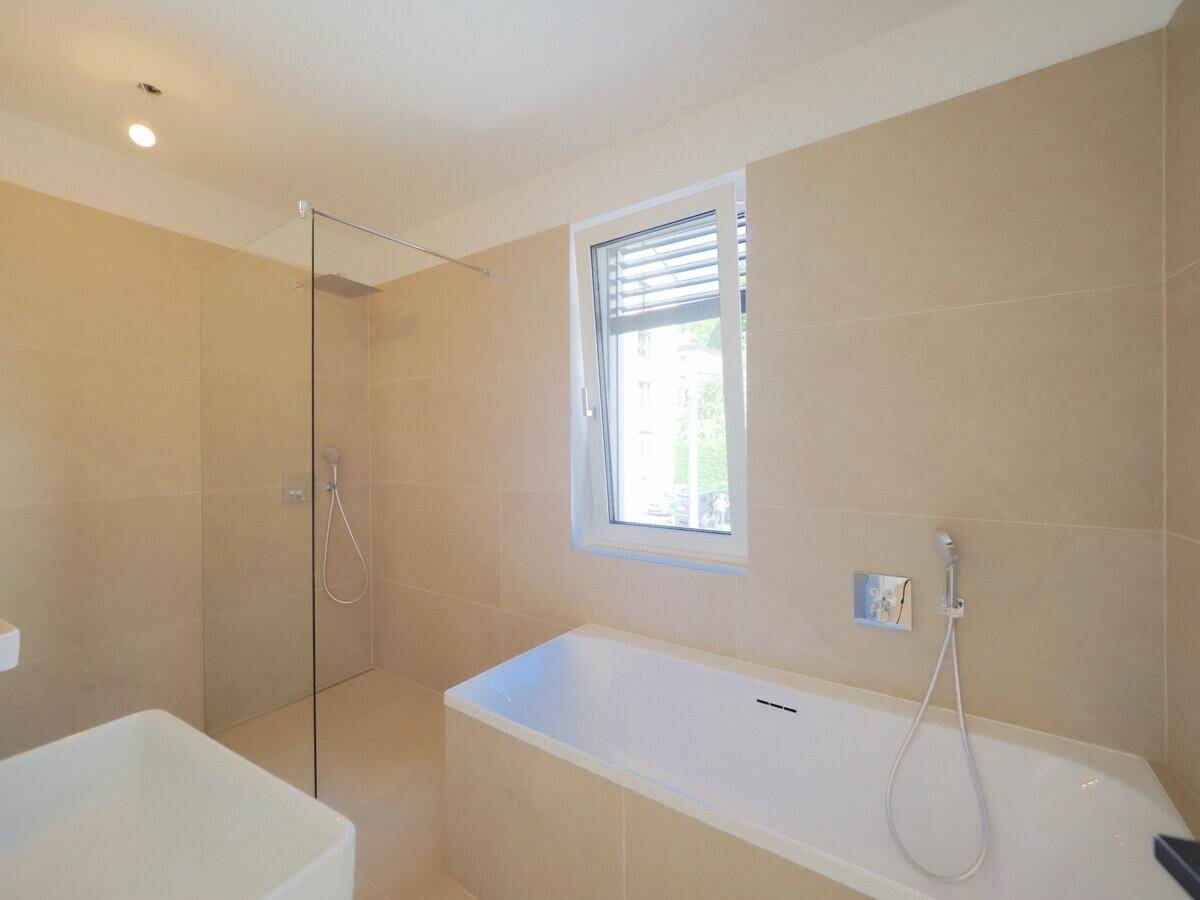Modernes Badezimmer mit Badewanne, Dusche und Fenster.
