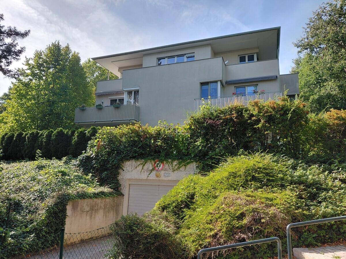 Ansicht der modernen Wohnanlage mit Tiefgaragenzufahrt, eingebettet in eine grüne Umgebung.