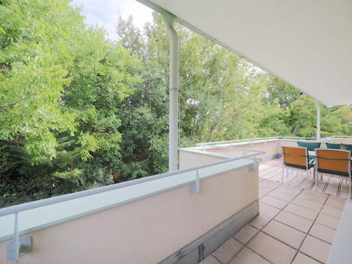 Weitläufiger Balkon mit Blick auf die umliegenden Bäume und die ruhige Nachbarschaft.