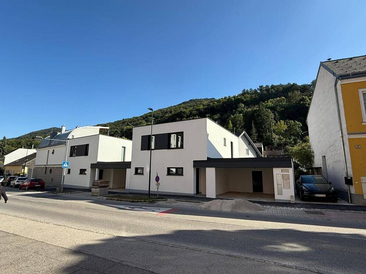 Moderne Neubauten mit klaren Linien und Carports an einer ruhigen Straße gelegen.