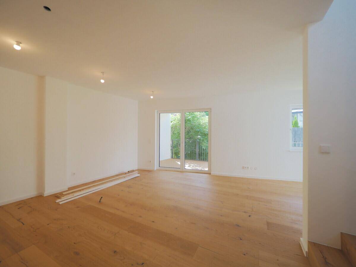 Geräumiges, helles Wohnzimmer mit Holzboden und Zugang zur Terrasse.
