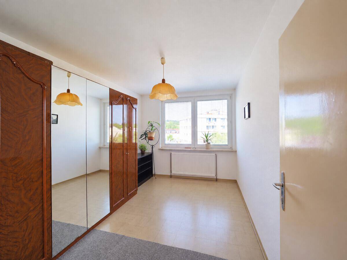Geräumiges Zimmer mit großem Spiegelschrank, hellen Fliesen und Blick auf die Umgebung.