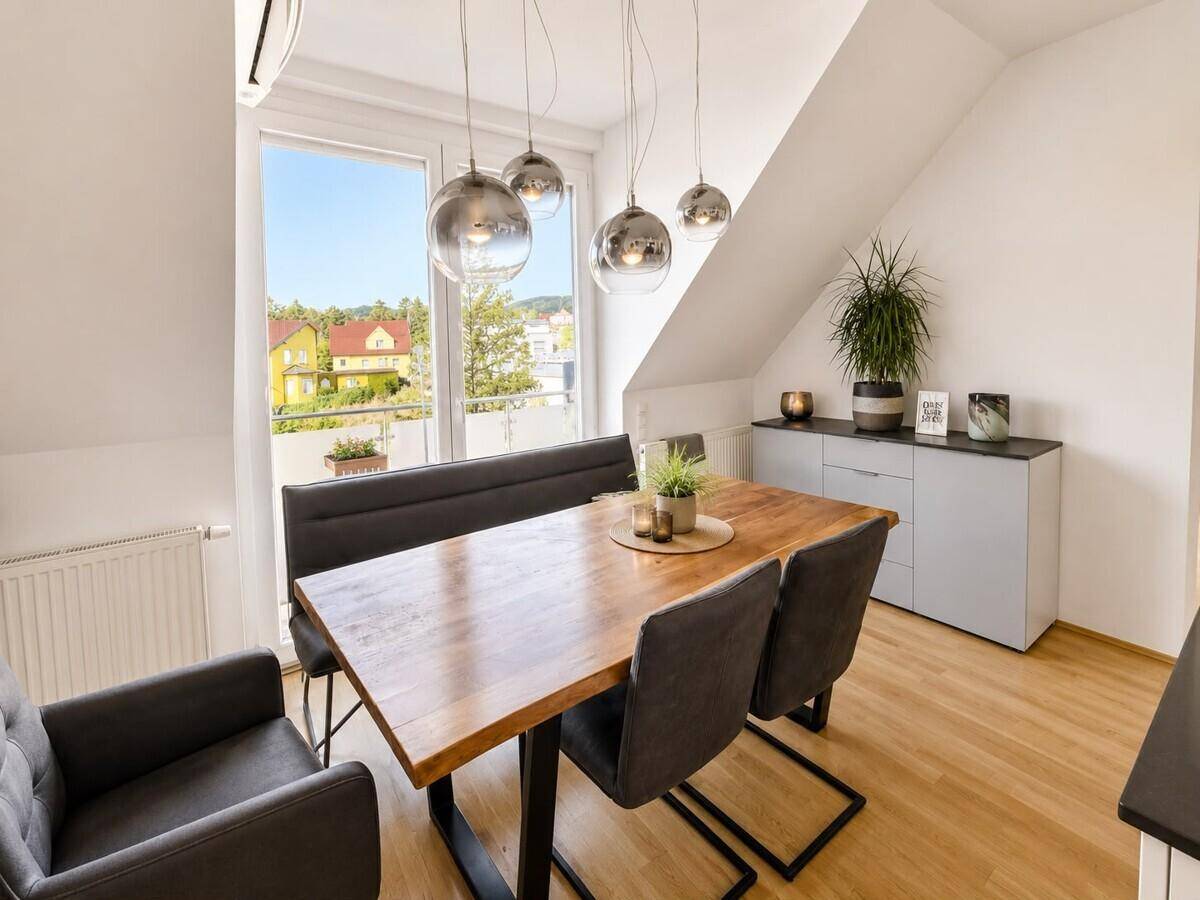 Gemütlicher Essbereich mit Holztisch und Sitzbank, direkt am Fenster mit Blick ins Grüne.