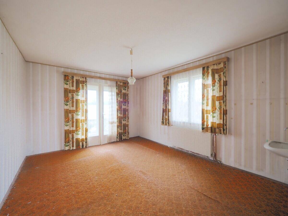 Schlafzimmer mit orangefarbenem Teppichboden und gemusterten Vorhängen, in älterem Zustand.