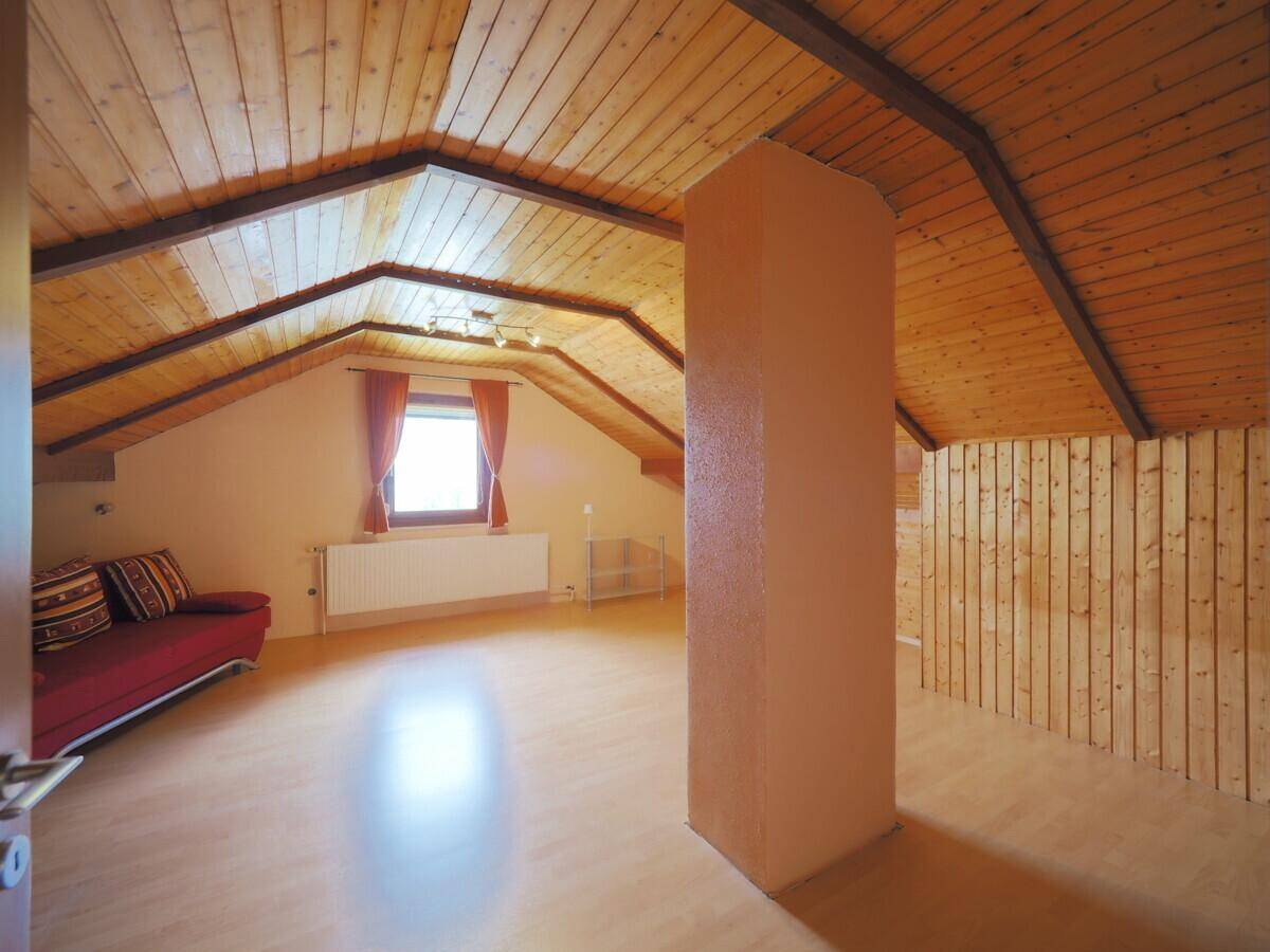 Gemütliches Dachzimmer mit Holzverkleidung an Decke und Wänden, ideal als zusätzlicher Wohnraum.