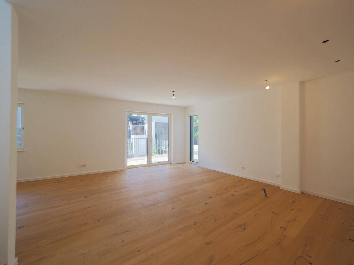 Lichtdurchfluteter Wohnbereich mit elegantem Holzboden und großen Schiebetüren, die viel Tageslicht hereinlassen.