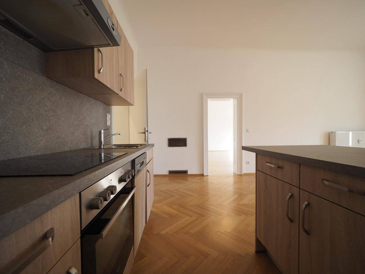 Moderne Einbauküche mit Holzfronten, Induktionskochfeld und integriertem Backofen.