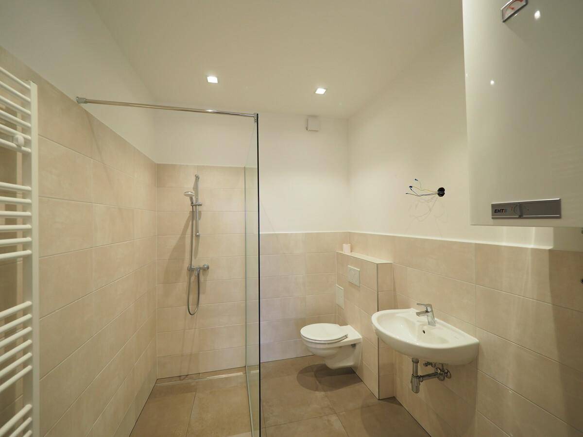 Modernes Badezimmer mit begehbarer Dusche, Wand-WC und beheiztem Handtuchhalter.
