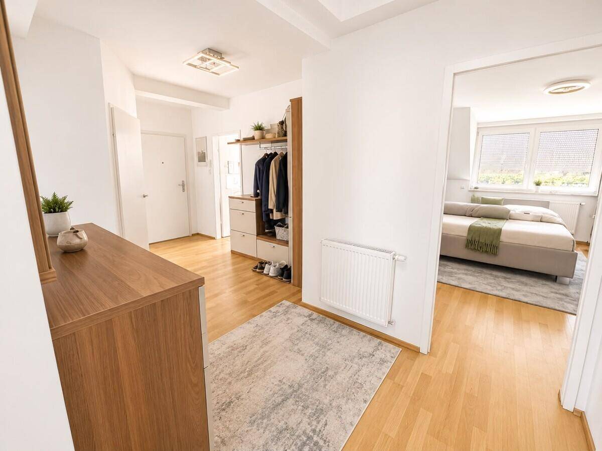 Heller Flur mit Holzfußboden und Garderobe, der den Zugang zum Schlafzimmer ermöglicht.