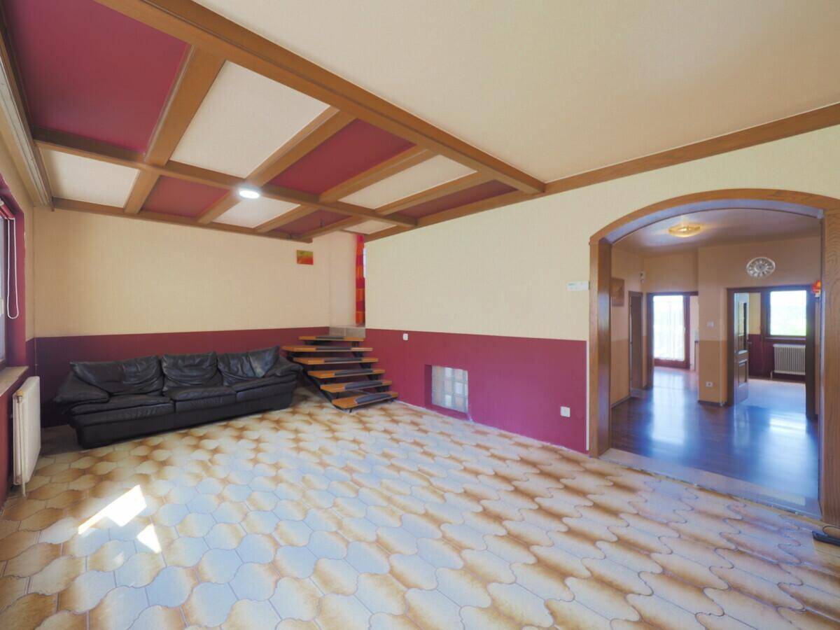 Geräumiges Wohnzimmer mit schwarzem Sofa, gemusterten Fliesen und dekorativer Holzdecke.