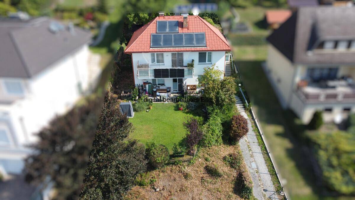 Luftaufnahme eines Hauses mit Solaranlage auf dem Dach und einem grünen Gartenbereich.