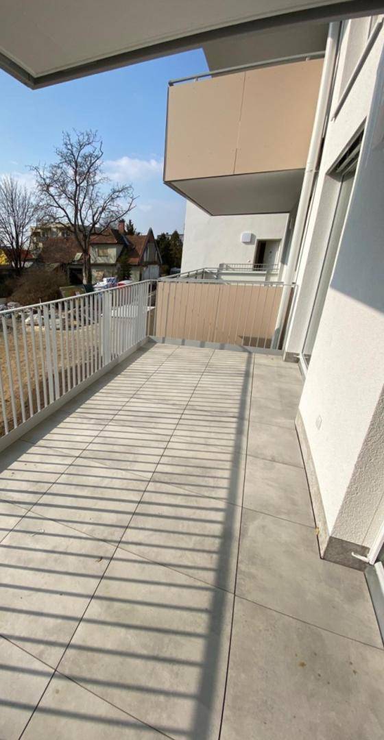 Geräumiger Balkon mit Fliesenboden und weißem Geländer, ideal für entspannte Stunden im Freien.