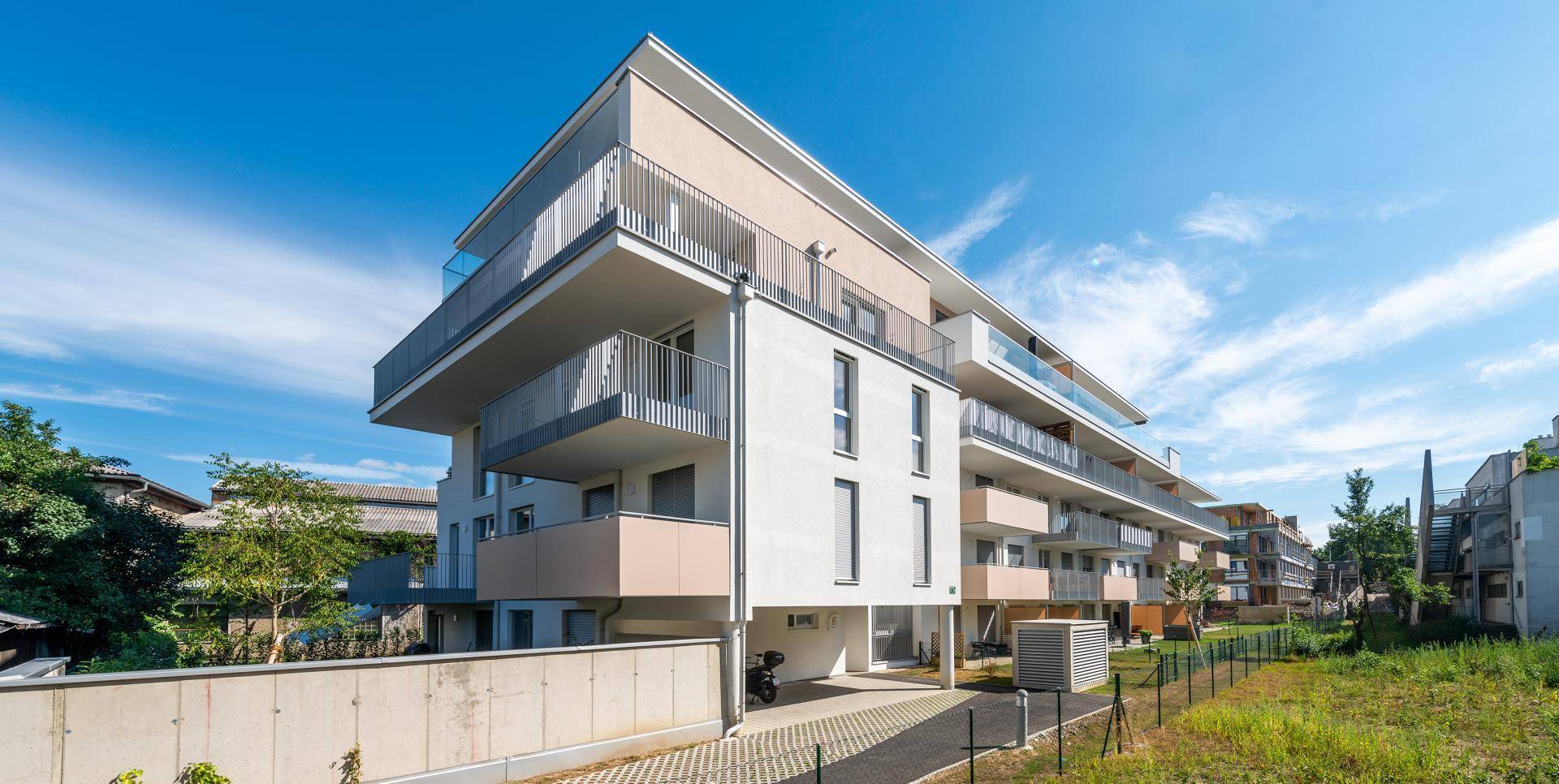 Architektonisch ansprechendes Mehrfamilienhaus mit modernen Balkonen und Zufahrt.