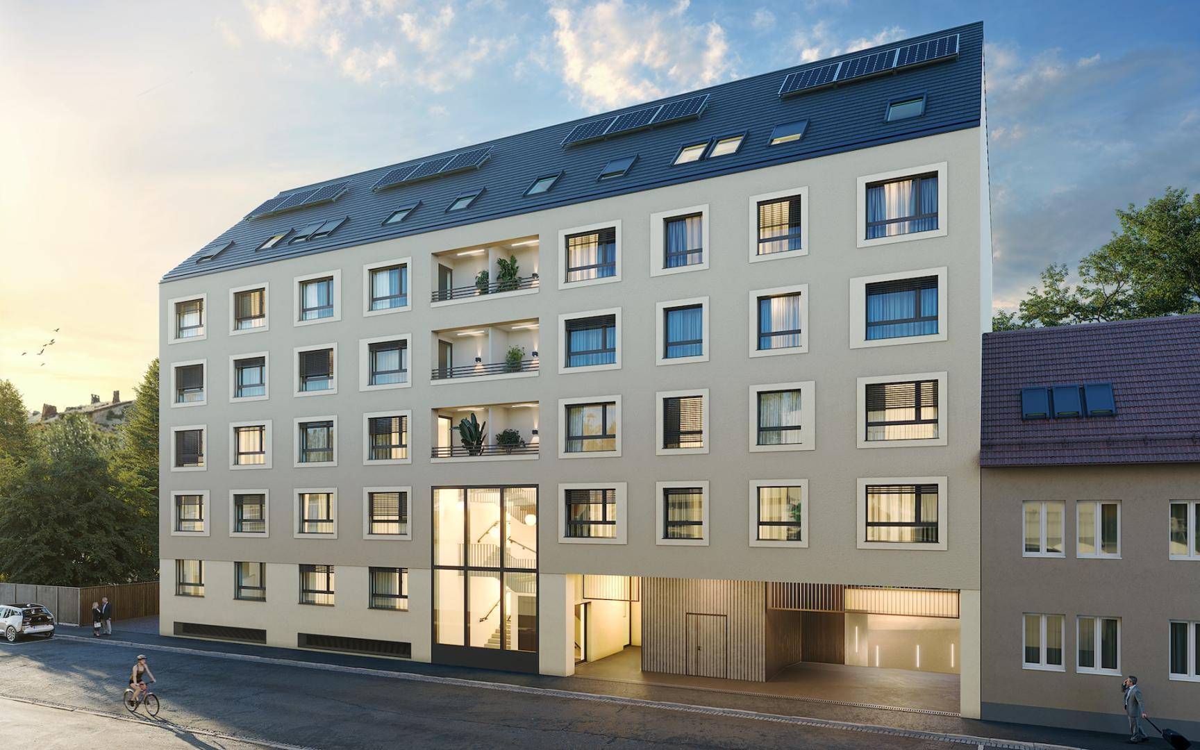 Moderne Wohnhausfassade mit großen Fenstern, Balkonen und Photovoltaikanlage auf dem Dach.