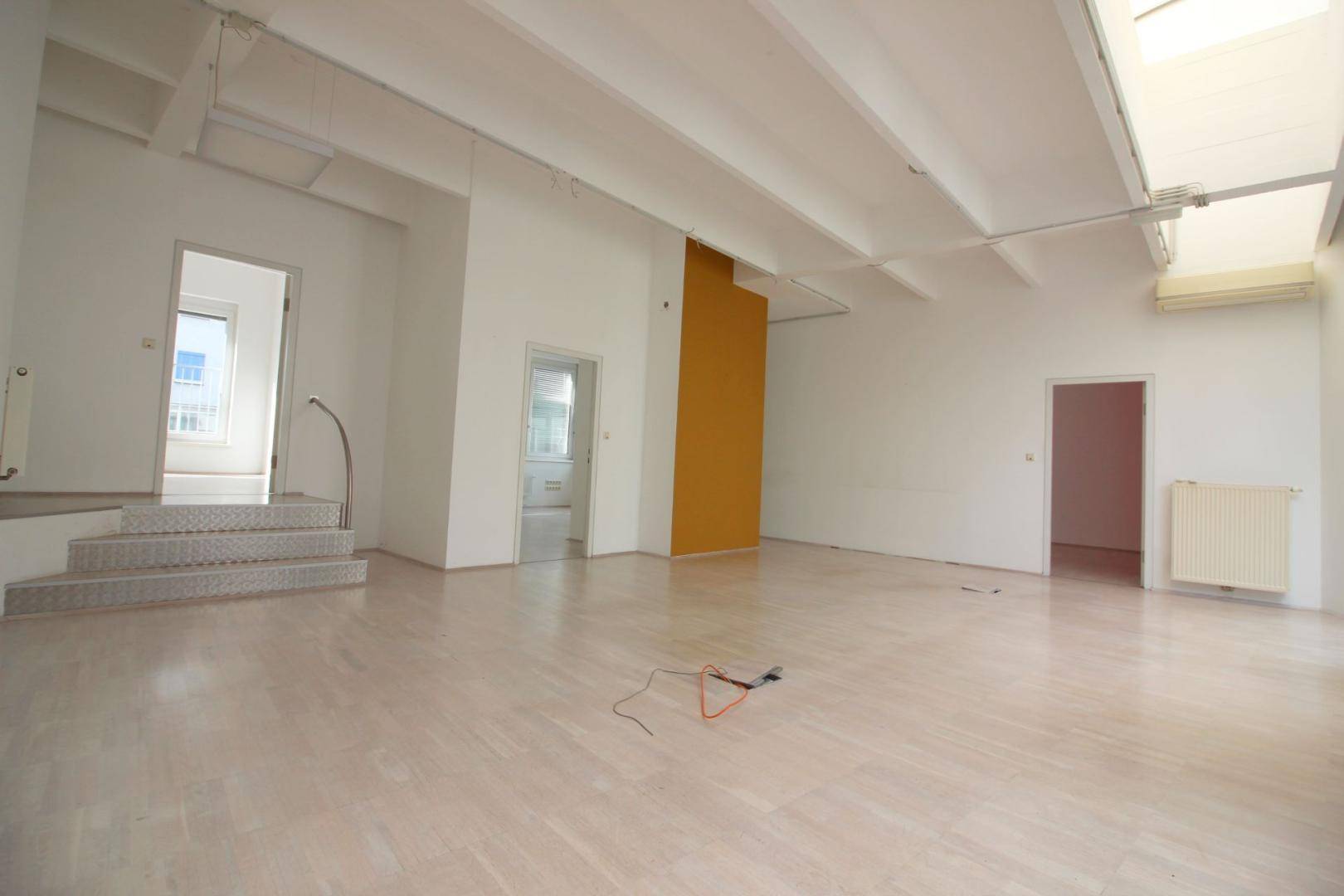 Großer, offener Büroraum mit hohen Decken, Treppe und verschiedenen Türen, bietet vielseitige Nutzungsmöglichkeiten.