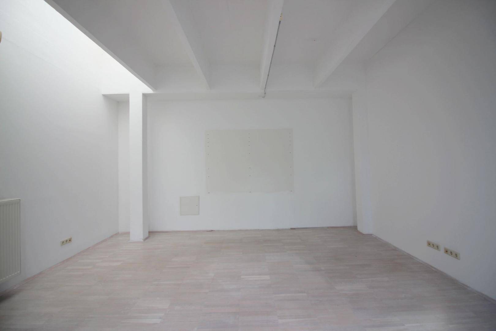 Leerer, heller Raum mit Holzboden und hohen Decken, bietet viel Platz für individuelle Einrichtung.