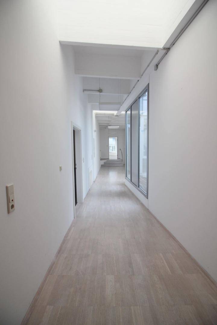Langer, heller Flur mit Holzboden und großen Fenstern, die viel Tageslicht in den Bereich lassen.